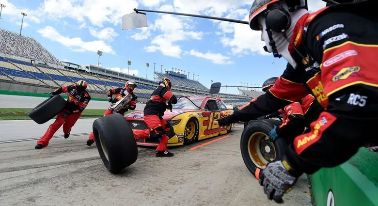 A NASCAR pit crew changing tyres, the nearest crew member wearing Mechanix gloves