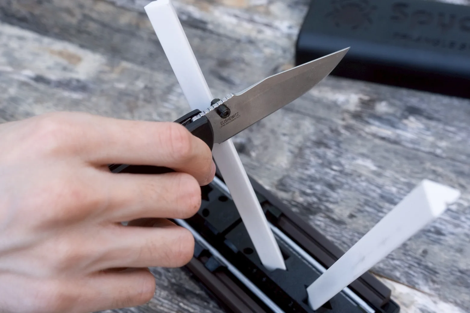 An Elishewitz folder in CPM MagnaCut being drawn down a white ceramic rod on the Sharpmaker